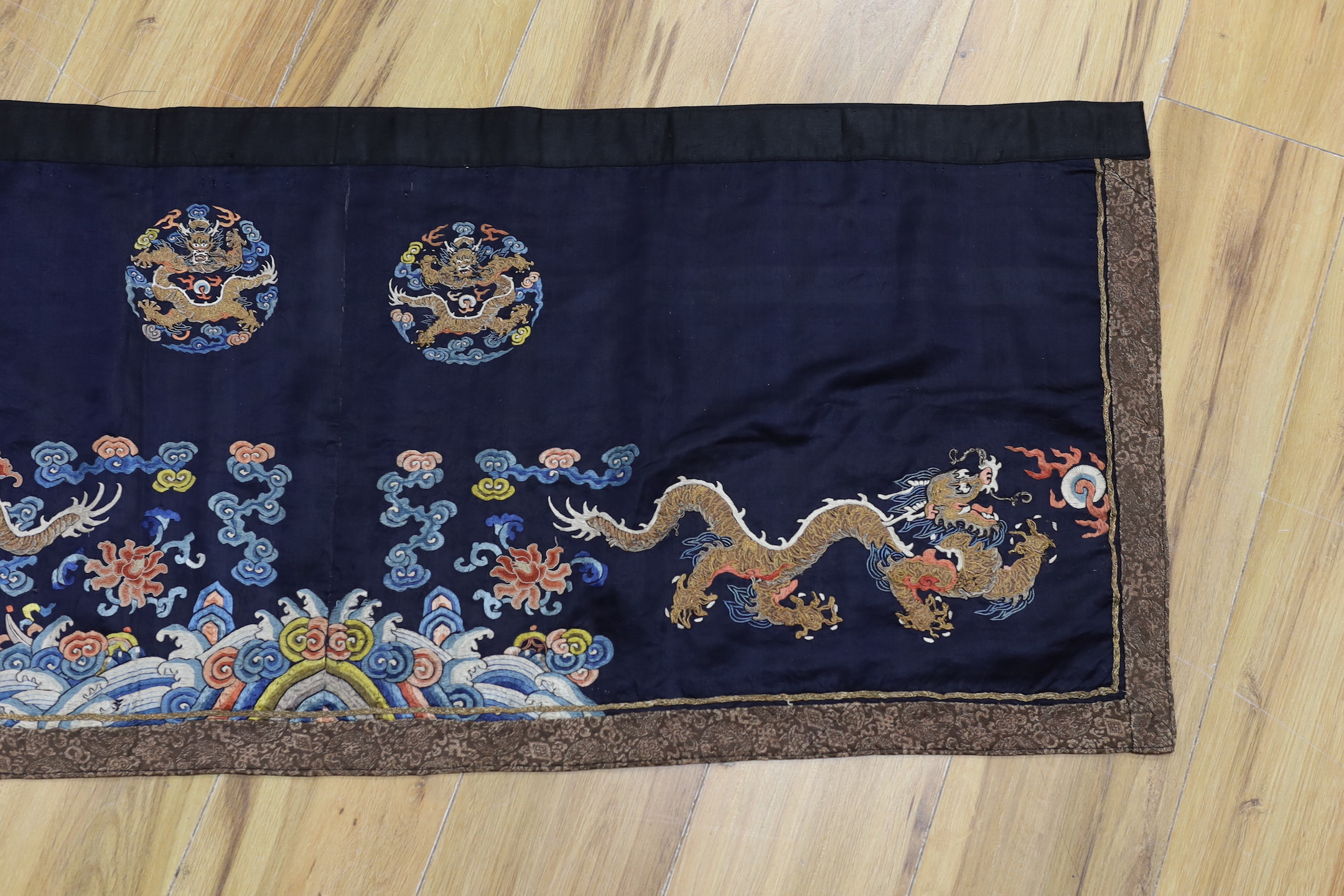 A Chinese long dark blue ground ‘dragon’ altar cloth, late Qing dynasty, polychrome embroidered, celestial dragons and mons amongst stylised clouds, 300 x 50cm